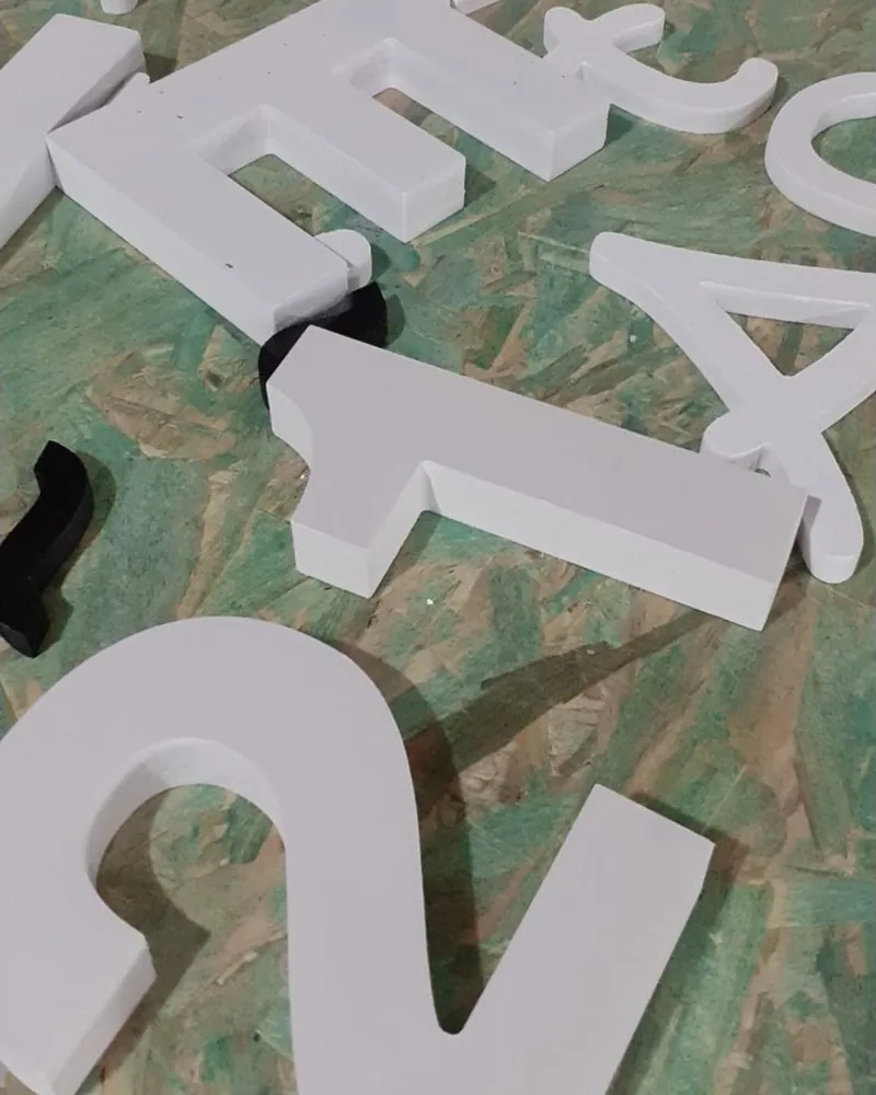 Letras e números recortados em PVC expandido branco sobre bancada